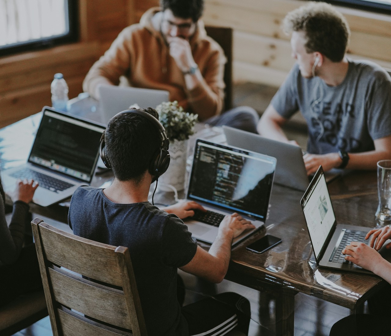 People collaborating around a table with laptops and notebooks